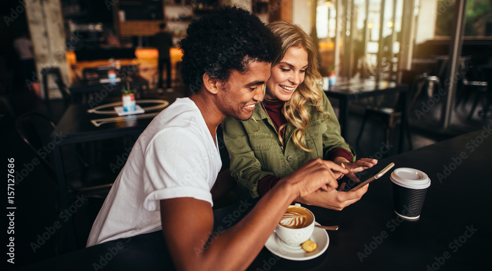 Best friends at coffee shop looking at smart phone