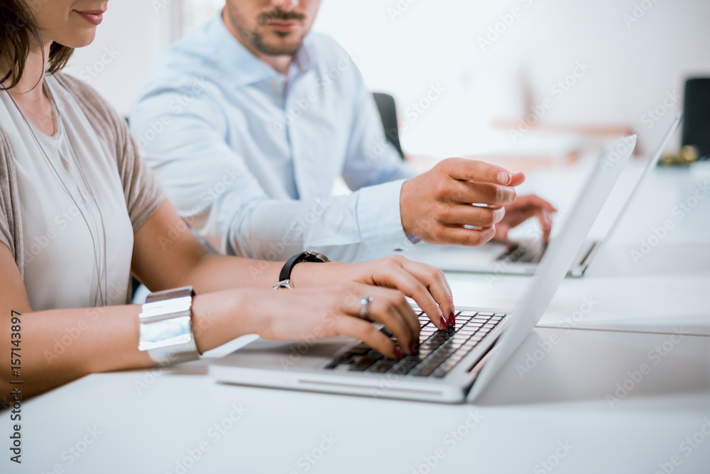 The fingers of a businessman pointing to a laptop computer screen for a female businesswoman.