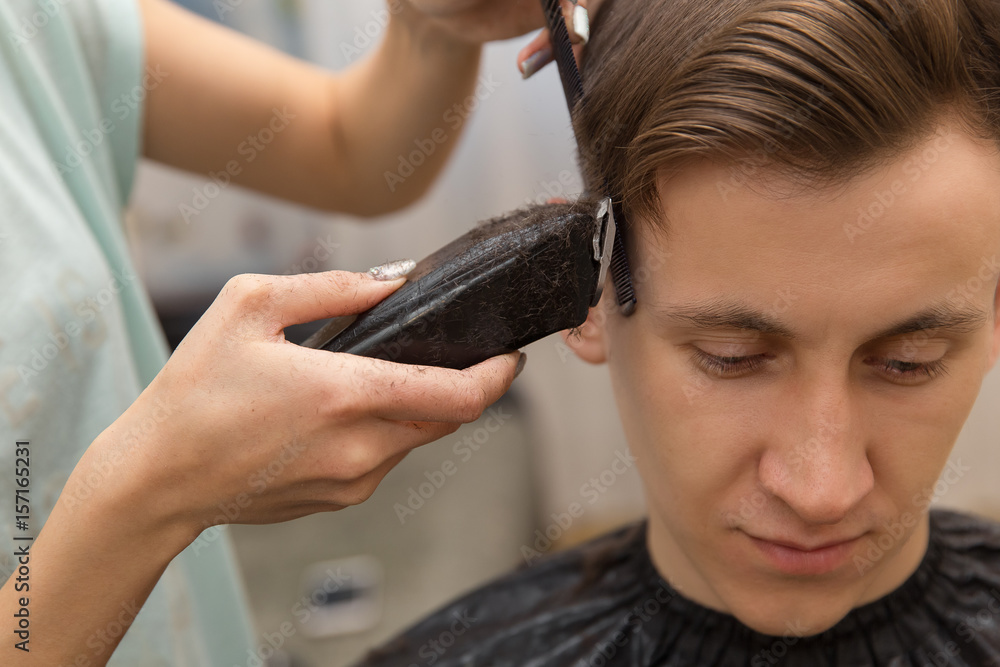 portrait of handsome man in barbershop. barber working with electric razor