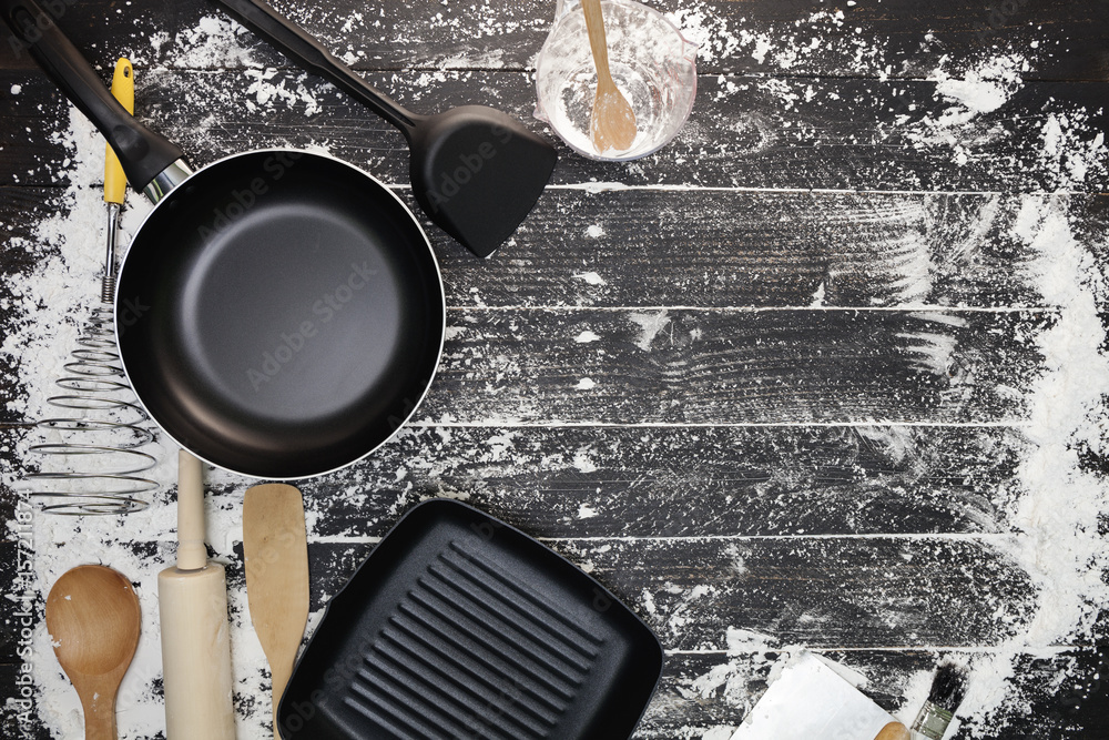 Cooking background with pans, flour, rolling pin,eggs,wooden spoons on black wooden background,cooki