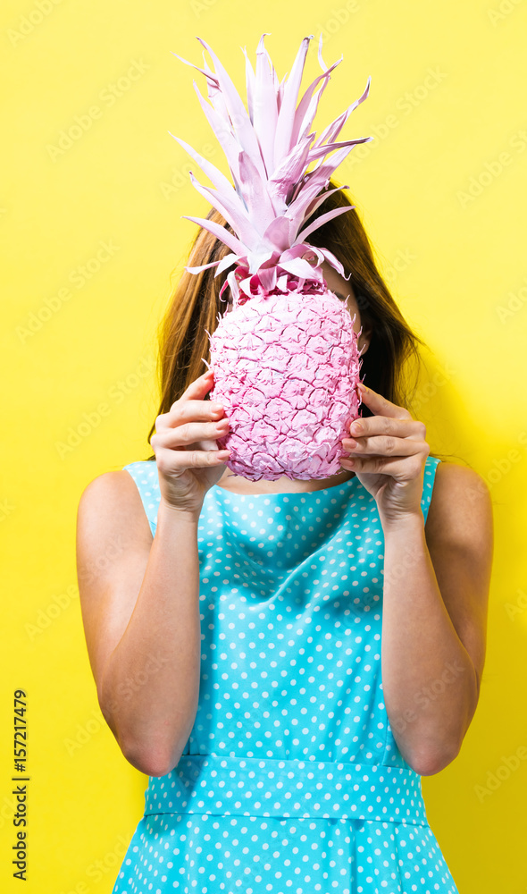 Happy young woman holding a pineapple