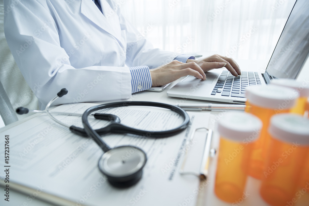 Female doctor is typing in laptop computer