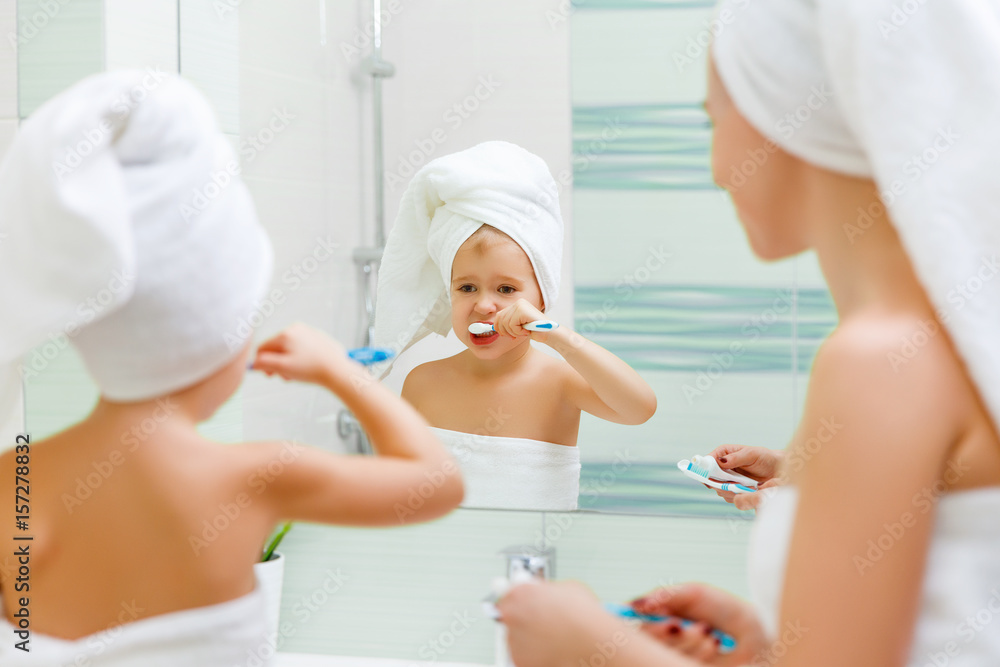 Mother and child daughter brush their teeth with  toothbrush.