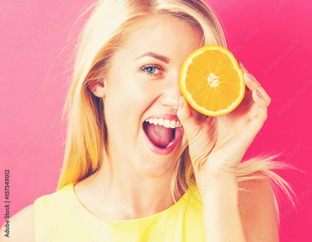 Happy young woman holding oranges halves