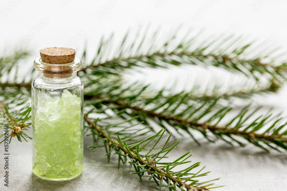 Bottles of sea salt and fir branches for aromatherapy and spa on white table background