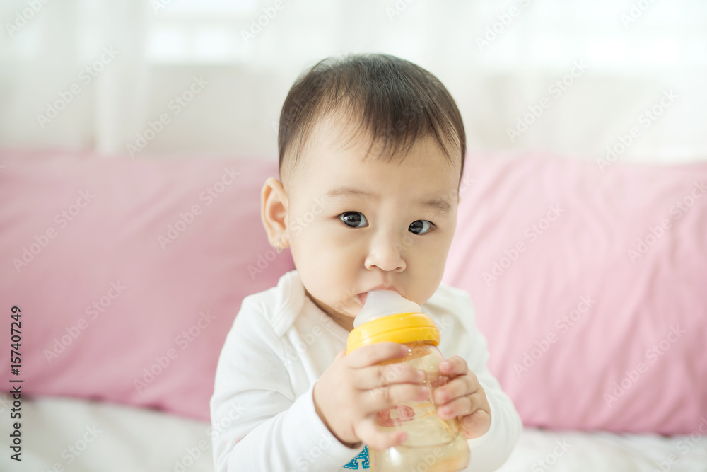 甜蜜的女婴在家里用奶瓶吮吸牛奶。