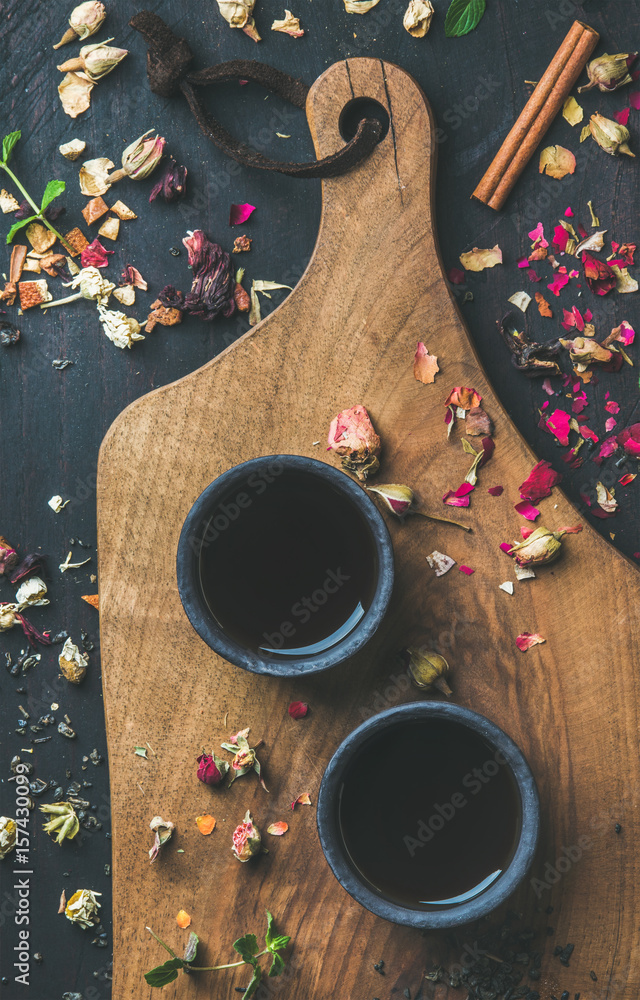 Chinese black tea in black stoneware cups on serving wooden board over black wooden background with 