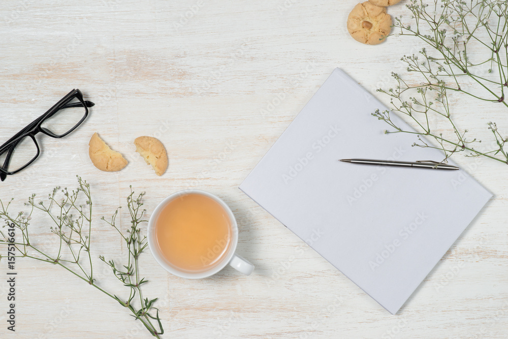 Top view of working desk with blank notebook with pen, coffee cup, mobile phone and cookies on woode