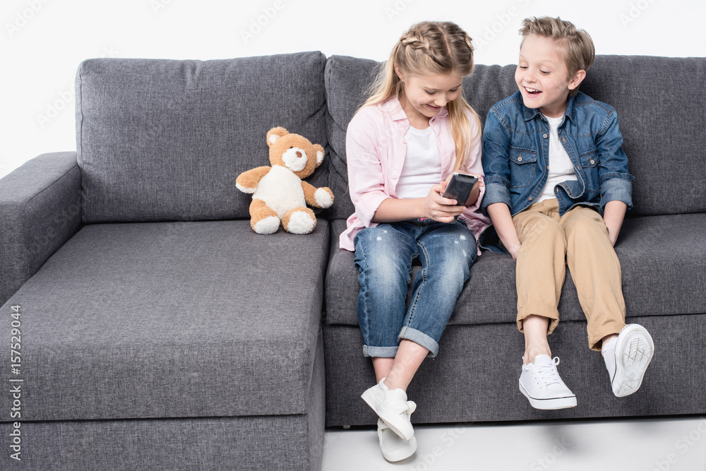 happy brother and sister watching tv while spending time together isolated on white