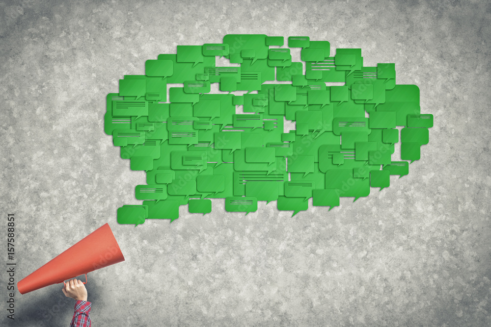 Hand of woman holding green paper trumpet and speech cloud coming out