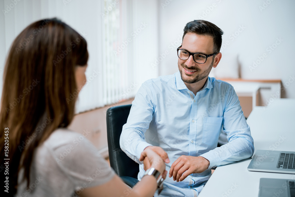 Young colleagues shaking hands in creative office