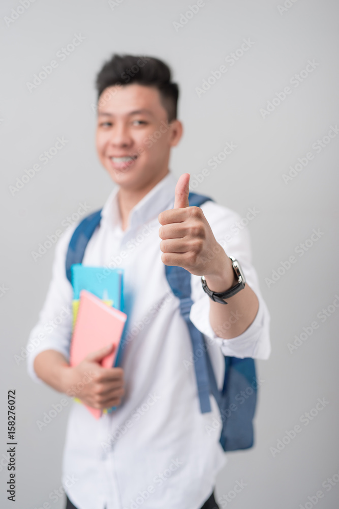 亚洲男学生在白色背景上做竖起大拇指的手势