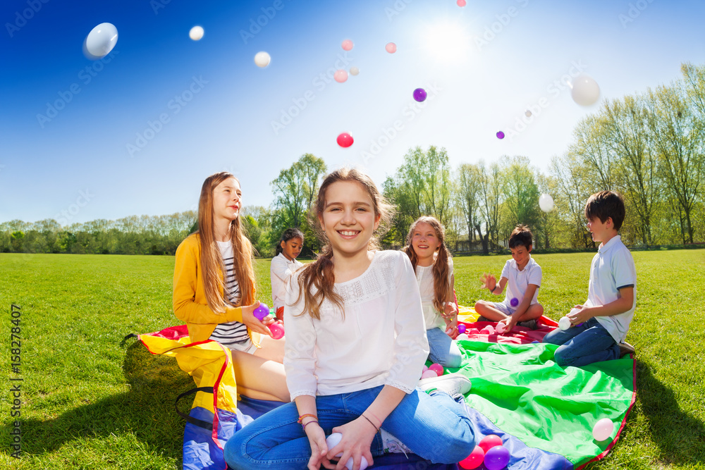 Girl throwing colorful balls playing with friends