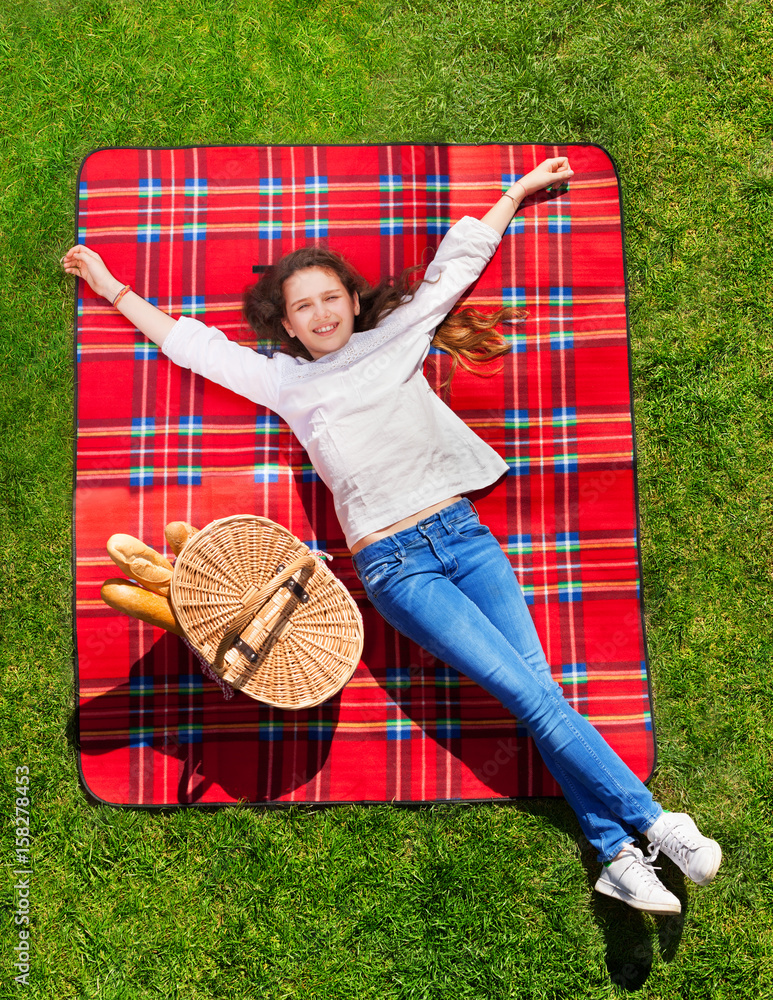 Girl relaxing on grassy meadow next to hand basket