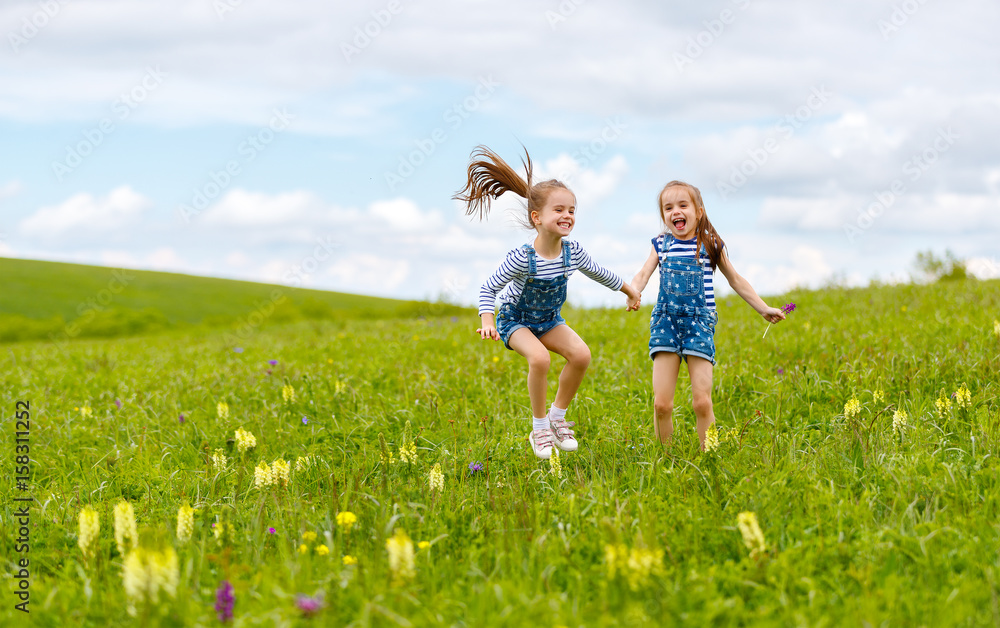 happy children twins sisters jumping and laughing  in summer