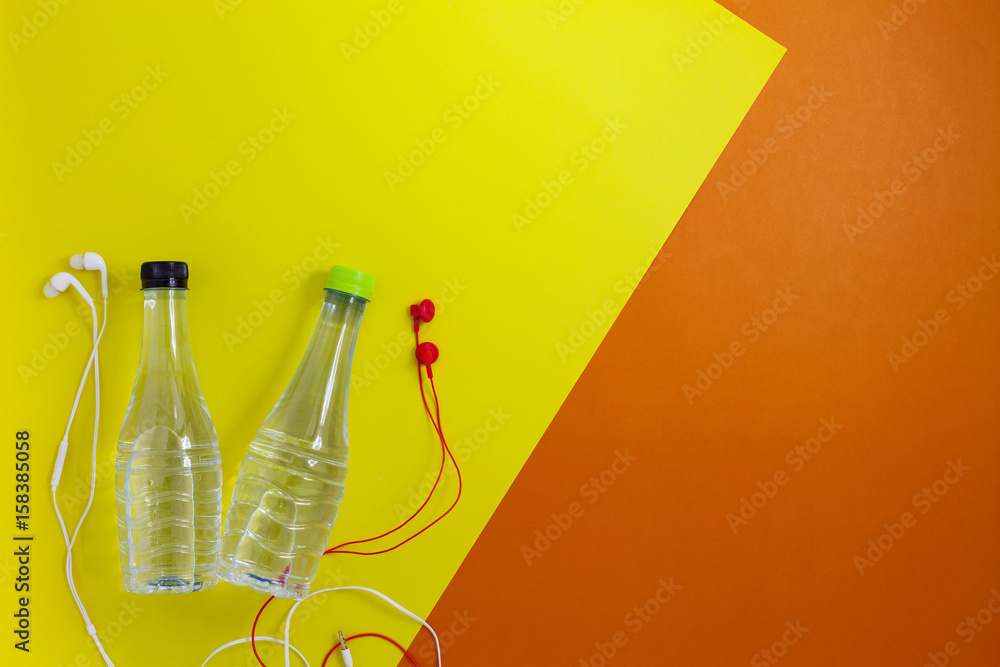 close up of water bottle and earphones on beautiful retro pastel color paper background,fitness back