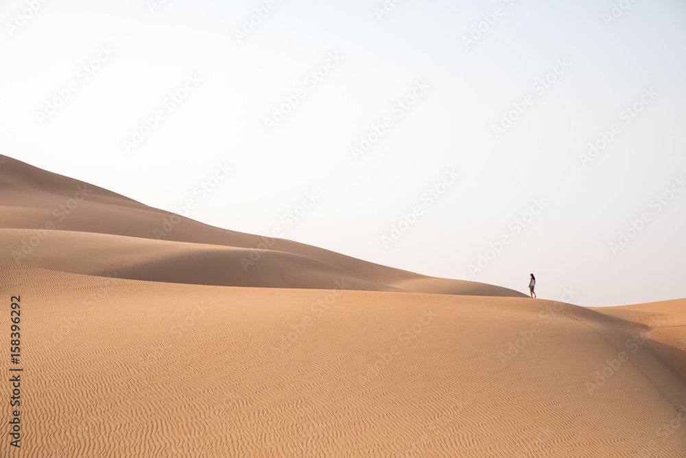 Beautiful woman hiking on giant sand dunes.