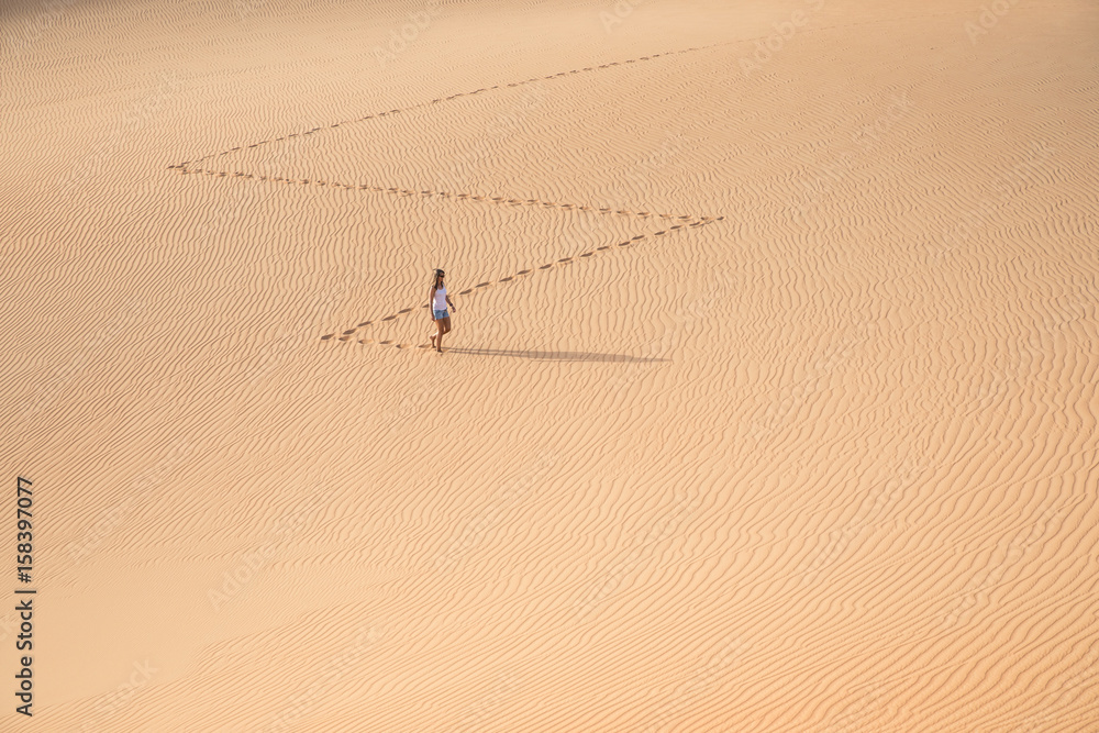 Beautiful woman hiking on giant sand dunes.