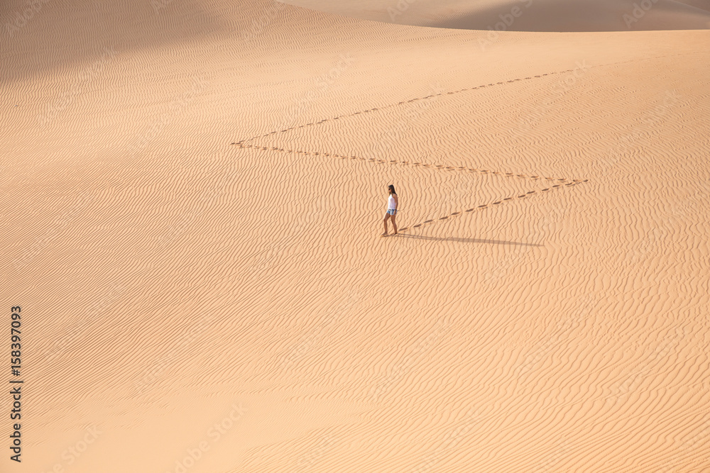 Beautiful woman hiking on giant sand dunes.