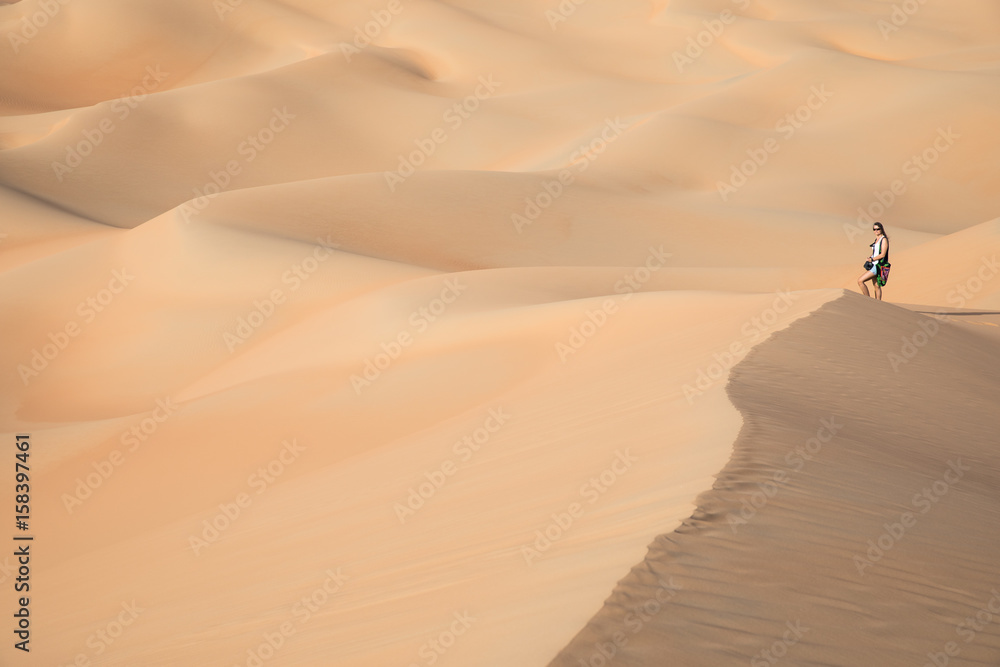 Beautiful woman hiking on giant sand dunes.