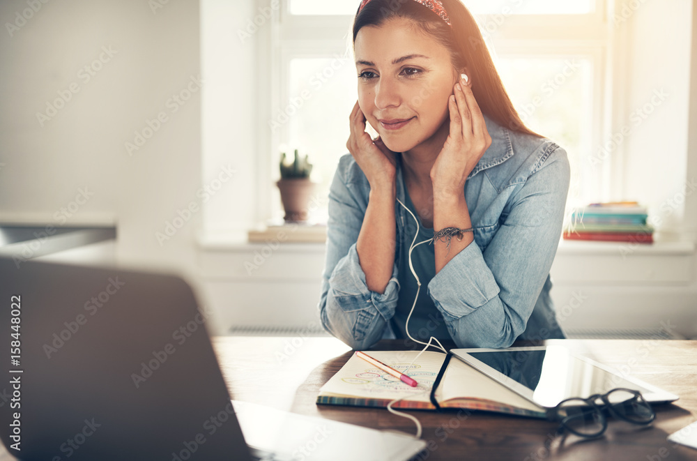 Employee woman with headphones looking at laptop in office