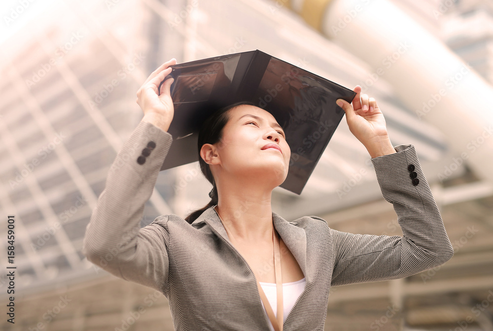 Beautiful business woman open cover sheet and put it on her head for blocking the sun.