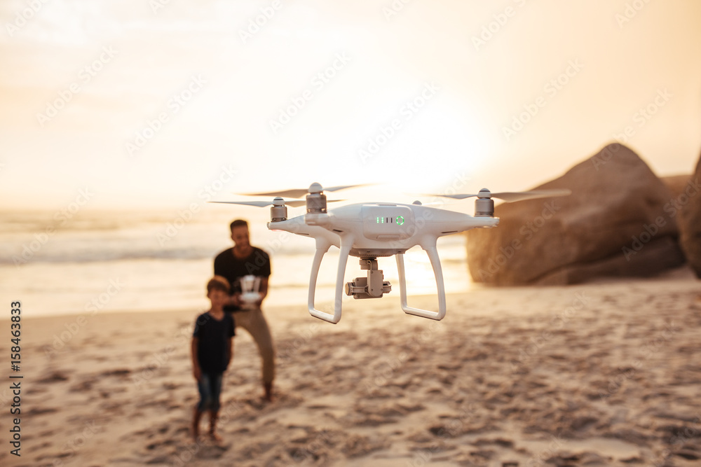 Drone being operated by father and son on beach