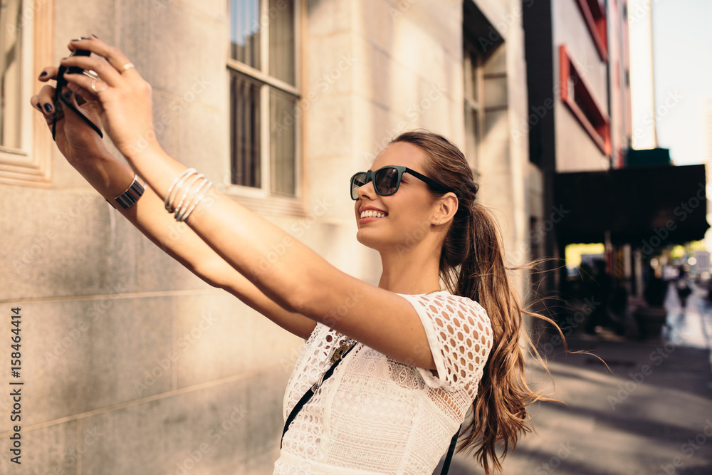 Young tourist recording selfie while walking in the street.