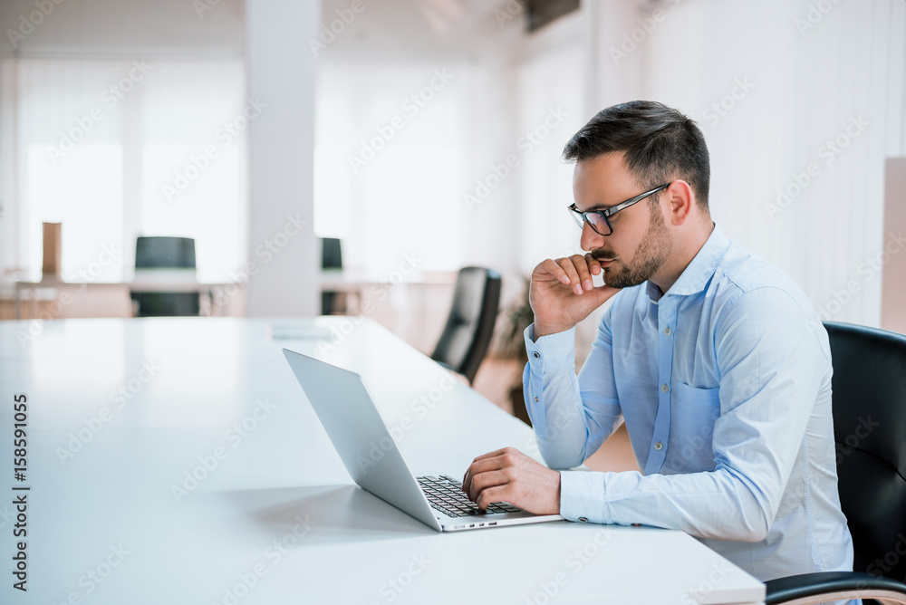 Handsome man working on project at modern office desk