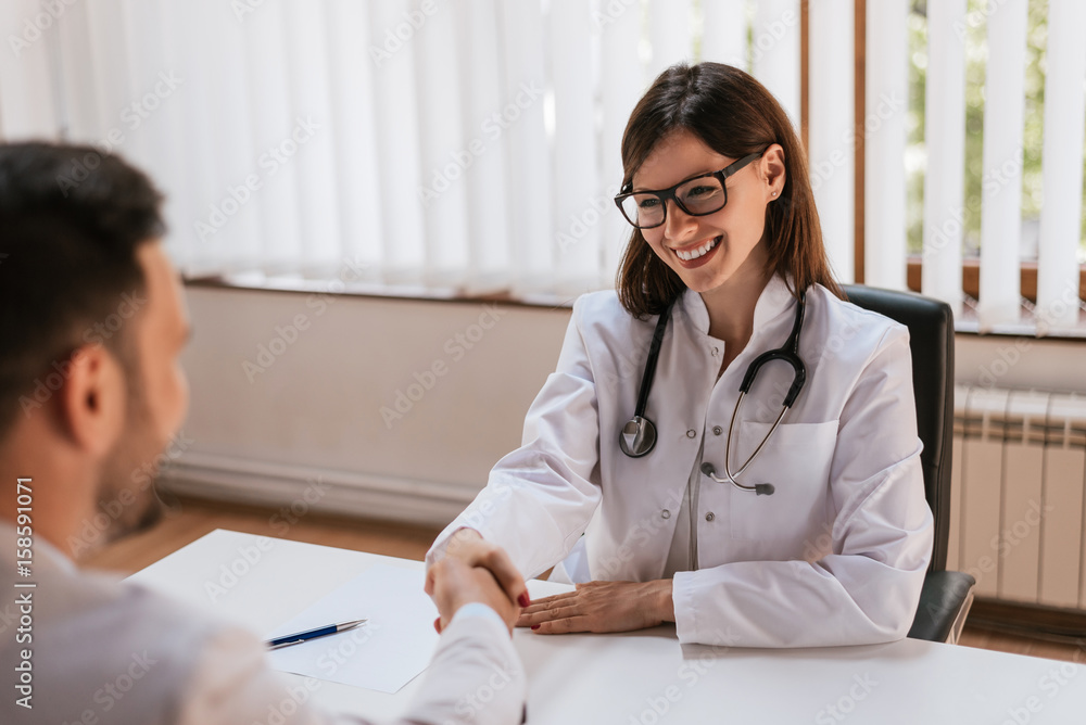 Doctor shaking hands to patient in the office at desk