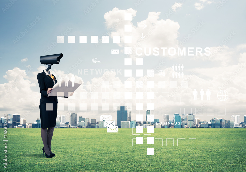 Camera headed woman standing on green grass against modern citys