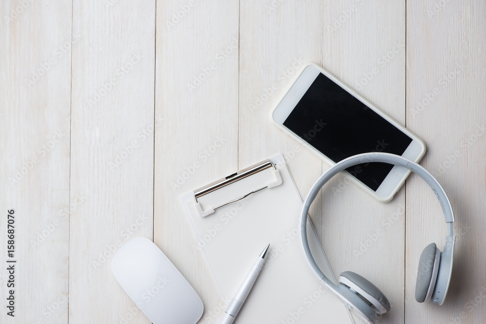 Notebook and smartphone on white table with headphone. View from above