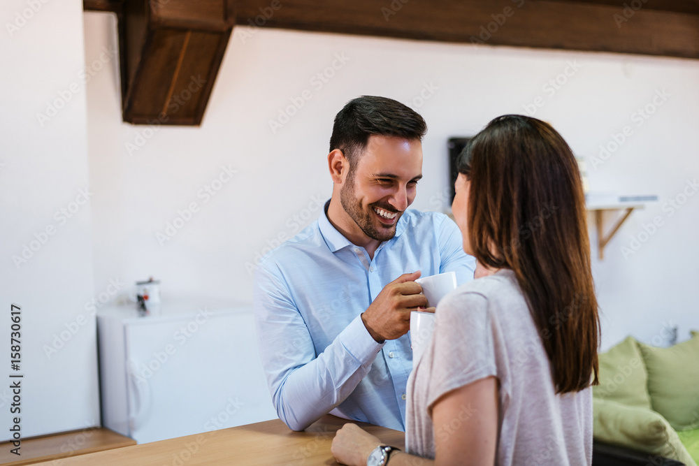 Beautiful young couple is talking and smiling while drinking coffee