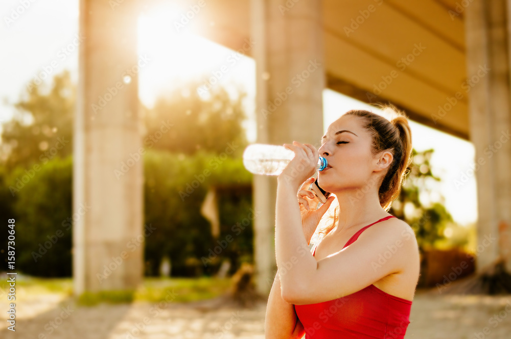 美丽的年轻女性跑步后喝水