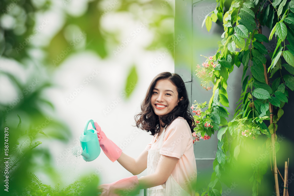 年轻的亚洲女园丁给植物浇水