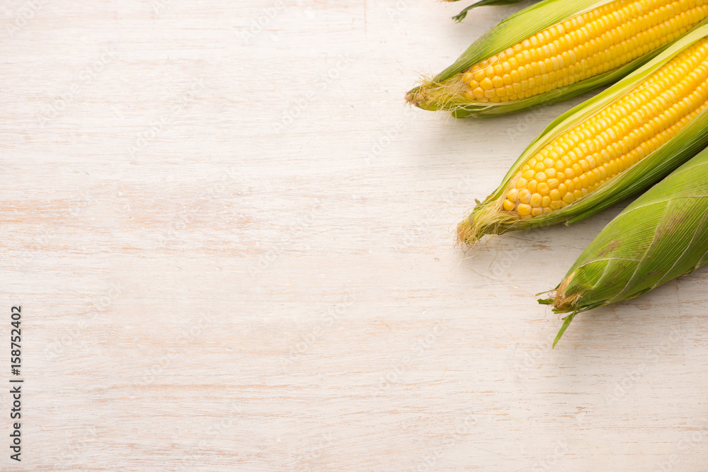 Sweet corns. Fresh corn on cobs on wooden table.