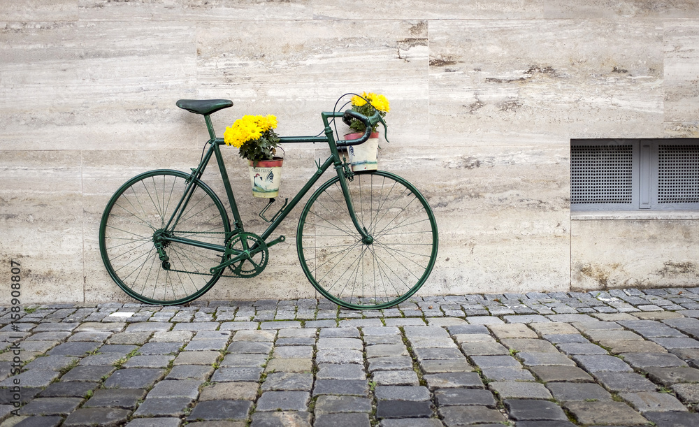 grünes Fahrrad mit Blumenschmuck in der Stadt