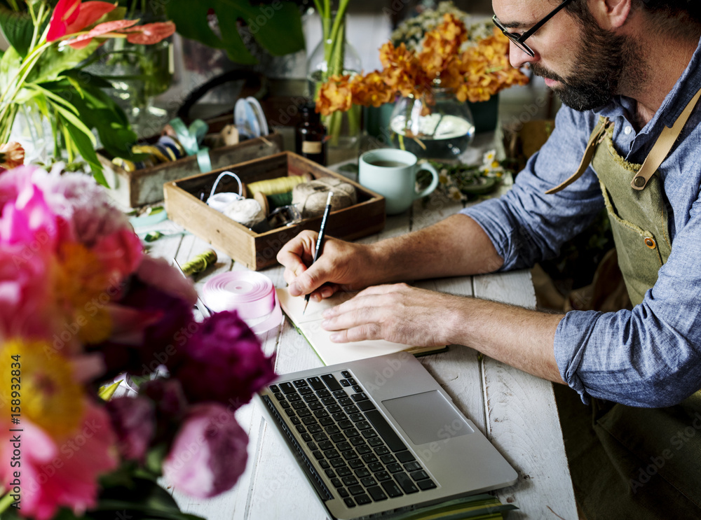 Man flower shop owner writing note on the table