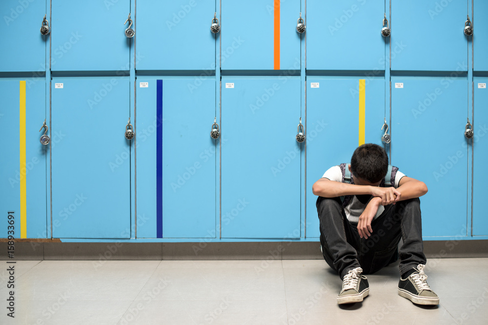 Boy sitting alone resting head on his arms