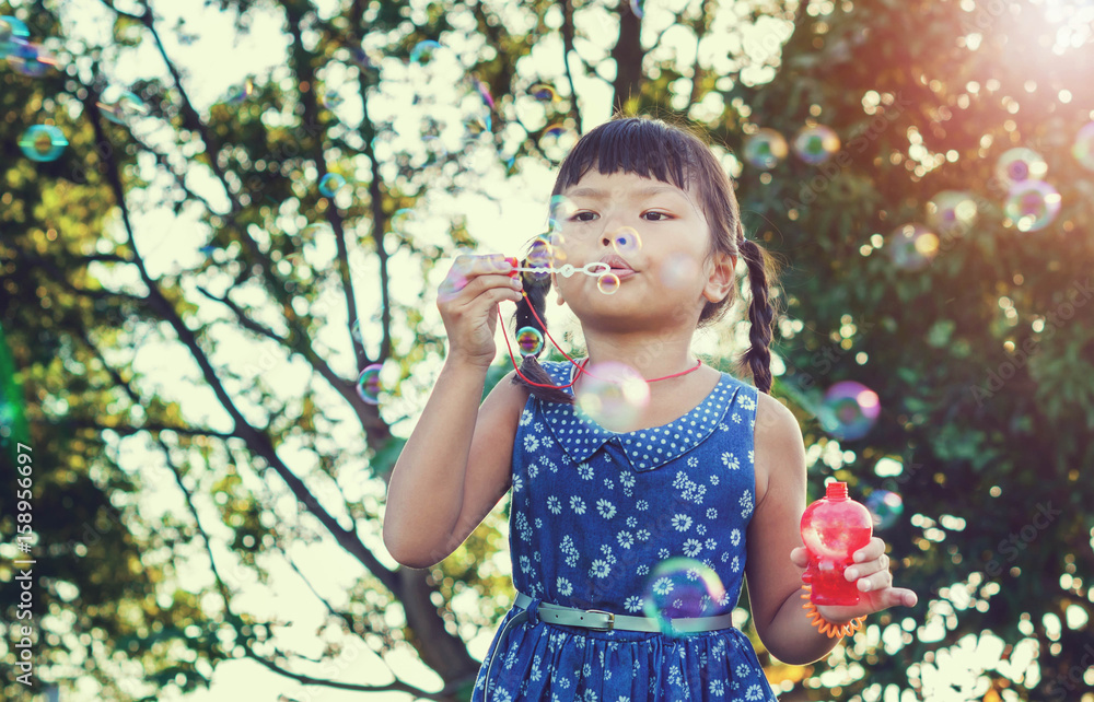 Asian little girl is blowing a soap bubbles, Outdoor Portrait