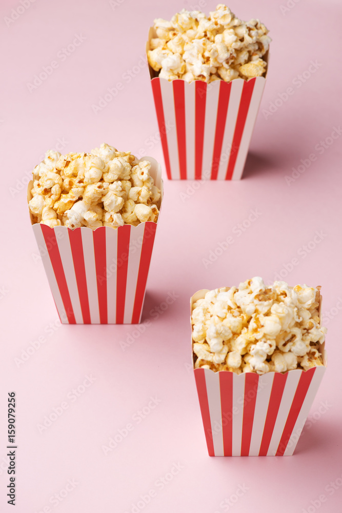 Popcorn in red and white cardboard box on the pink background.