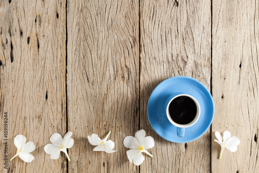 coffee cup and frangipani flowers on old wooden background.