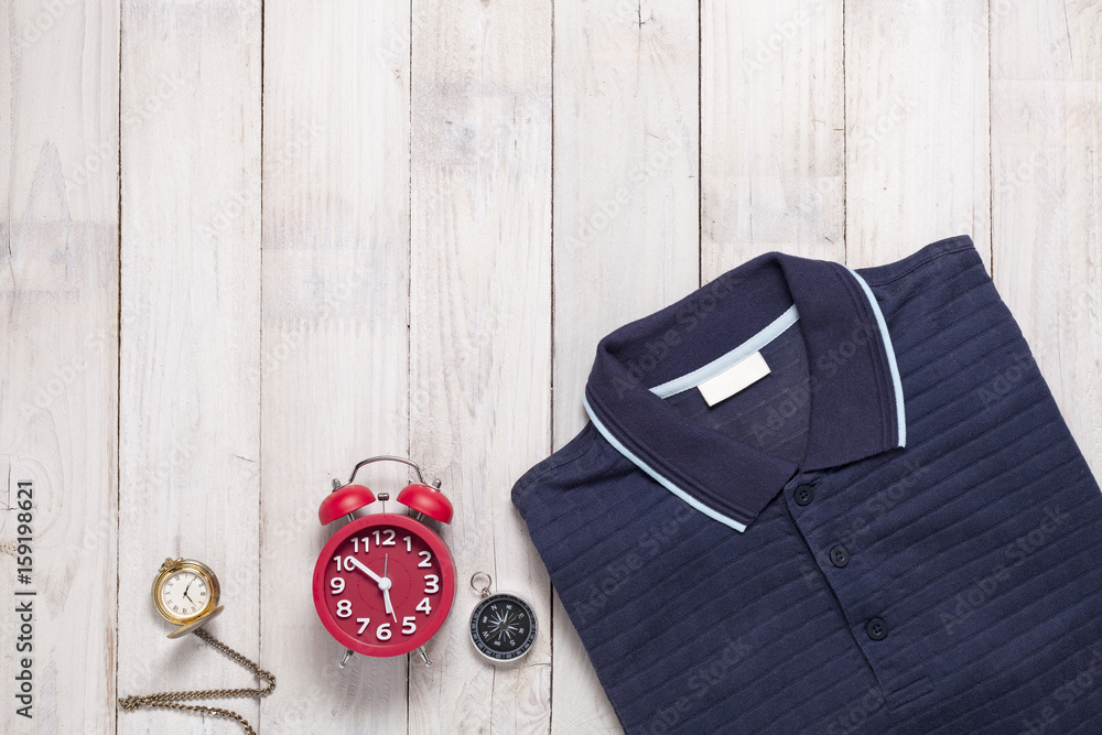 Polo shirt with alarm clock,pocket watch,compass on white wooden background.