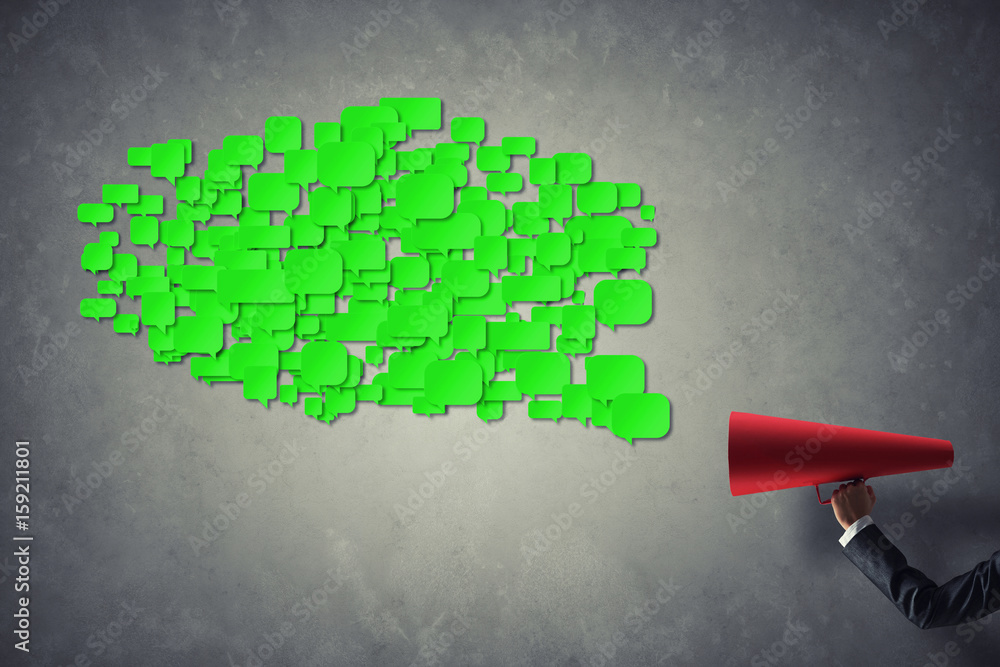 Hand of businesswoman holding red paper trumpet and speech cloud