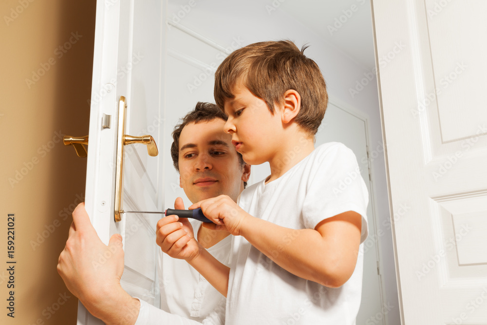 Young father helping his son to fix door-handle