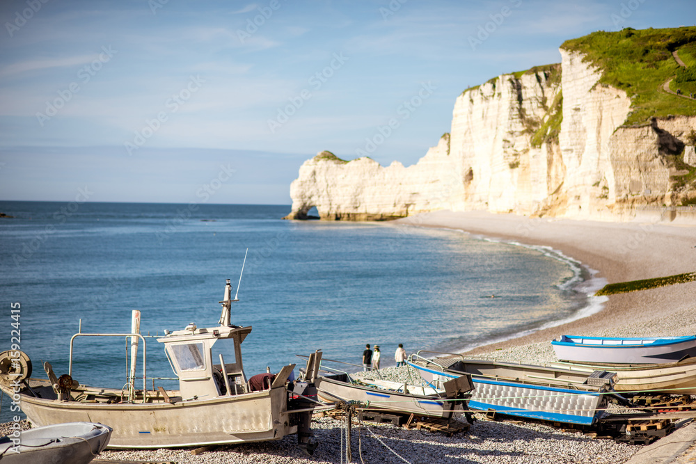 Landscape view on the rocky coastline and beach with old boats in Etretat town in France