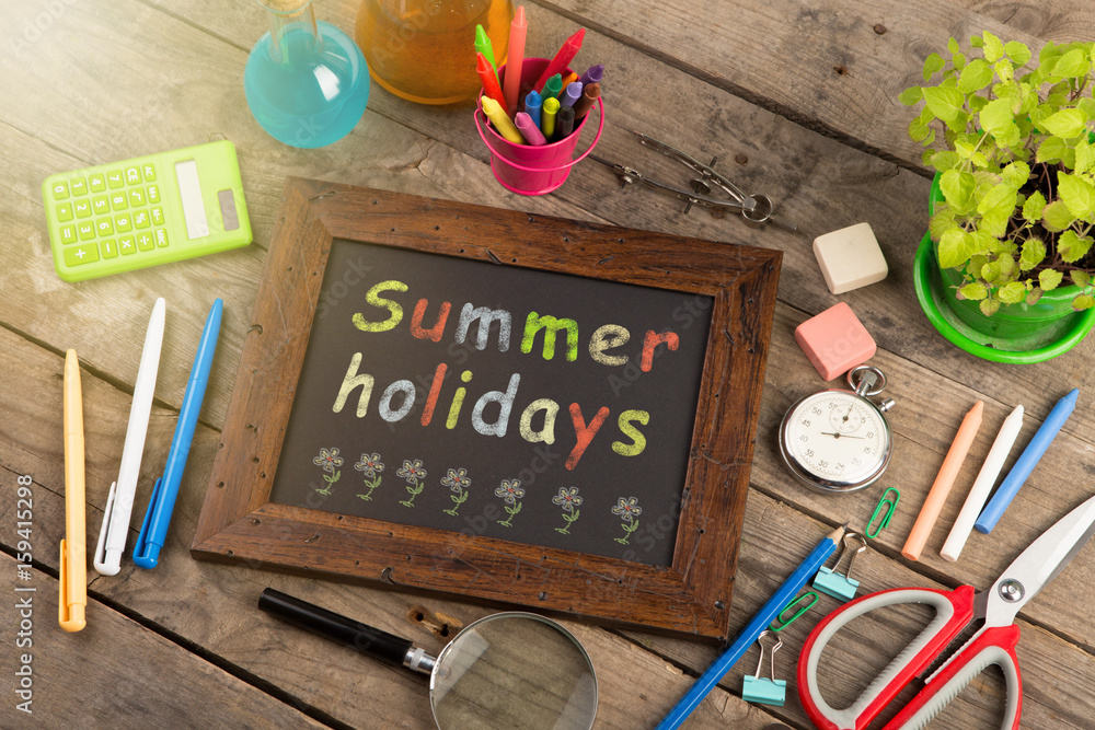 Summer holidays concept - school supplies on the wooden desk