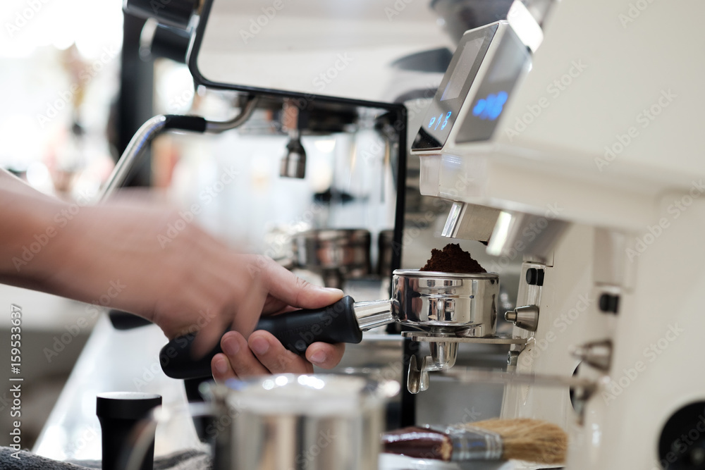 man holding portafilter loaded with grinded coffee and preparing fresh espresso