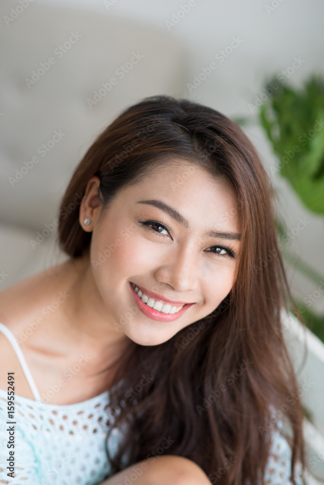 Smiling beautiful asian woman relaxing in the morning sitting indoors.