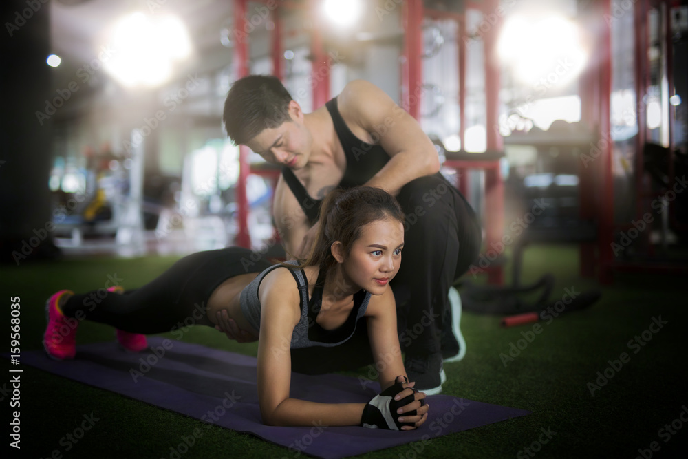 Asian trainer and lady take personal training in fitness club